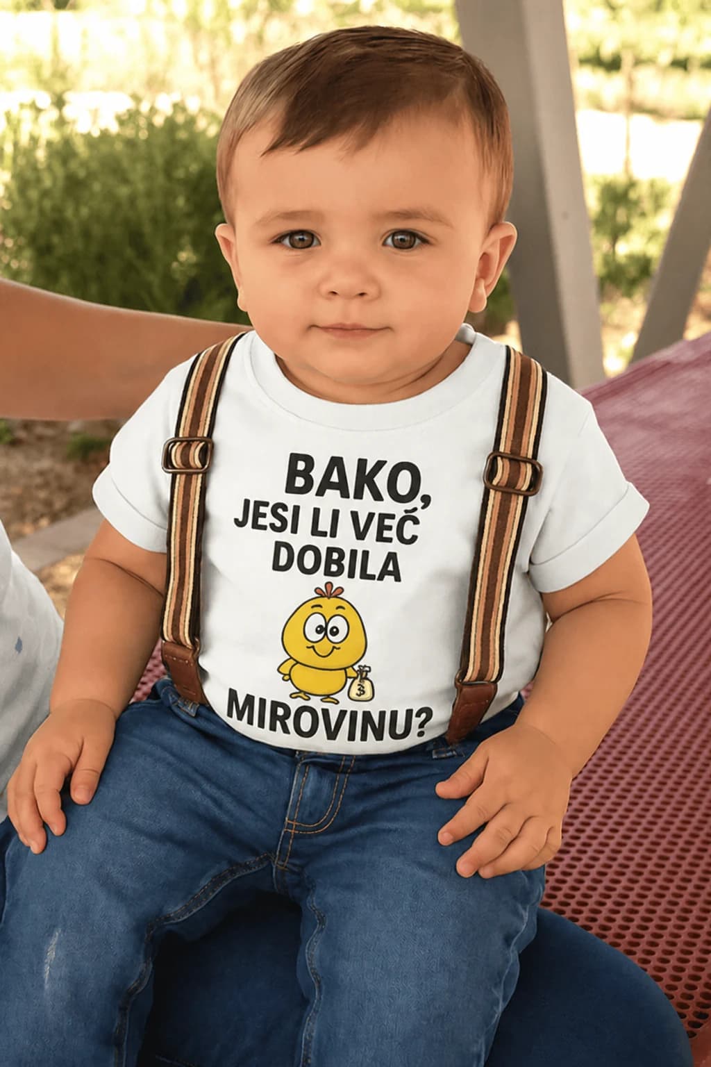Dijete u bijeloj majici s natpisom Bako, jesi li već dobila mirovinu i pilićem s vrećicom novca