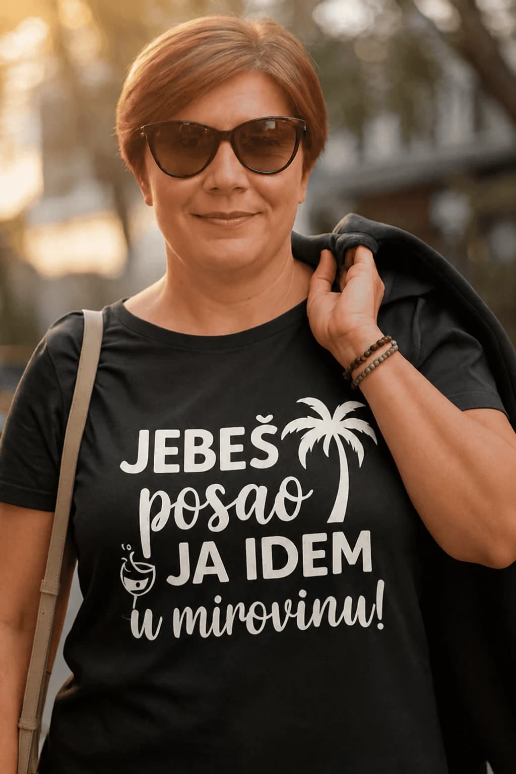 Žena sa sunčanim naočalama u crnoj majici s natpisom „Jebeš posao, ja idem u mirovinu!“ i palmom
