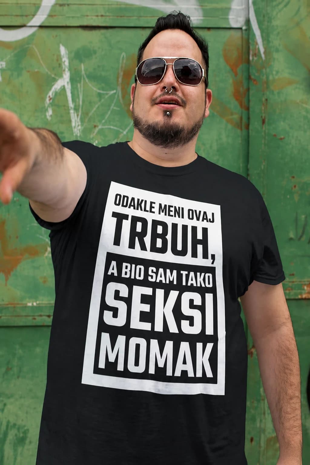 Muškarac sa sunčanim naočalama u crnoj majici s natpisom „Odakle meni ovaj trbuh, a bio sam tako seksi momak“