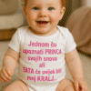 Prikaz sretne bebe u pidžami s natpisom o princesama i kraljevima.