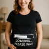 Samostojeća trudna žena u crnoj majici s natpisom "Loading... Please Wait".