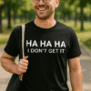 Osmiješan muškarac u parku s crnom majicom s natpisom "HA HA HA I DON'T GET IT".