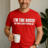 Vlasnik crvene majice sa tekstom "I'm the boss! My wife said I could be" drži bijeli šalica za kavu.