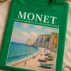 Majica s natpisom MONET ÉTRETAT: THE BEACH AND THE FALAISE D'AMONT i impresionističkim motivom obale