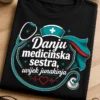 Majica za medicinsku sestru s natpisom Danju medicinska sestra, uvijek junakinja i modernim medicinsko-hero grafičkim motivom u teal, bijeloj i crvenoj